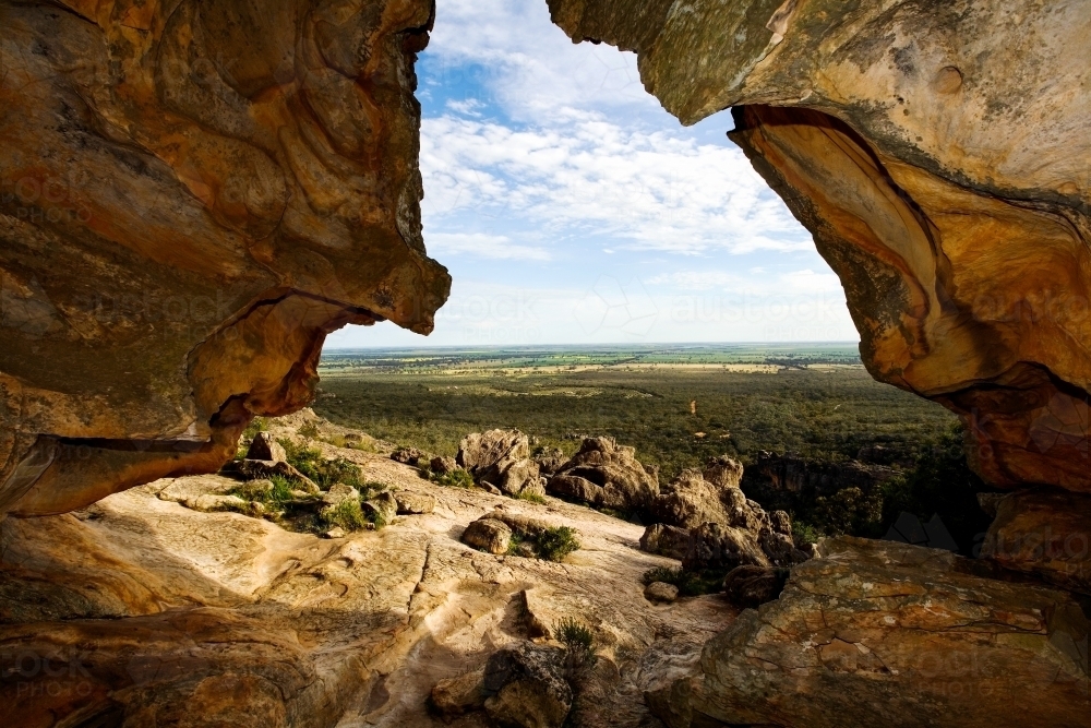 View out of cave in mountain looking over a valley - Australian Stock Image
