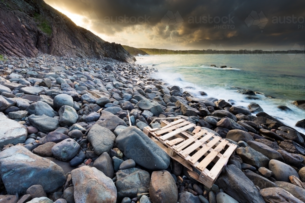 View out to ocean from a rocky shoreline with a washed up pallet on the rocks - Australian Stock Image