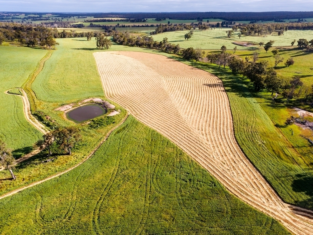 View over farm landscape with mown hay forming abstract patterns - Australian Stock Image