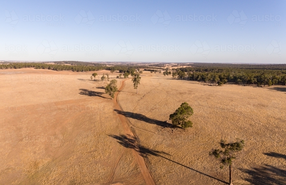 view over farmland with gravel track winding through dry paddocks - Australian Stock Image