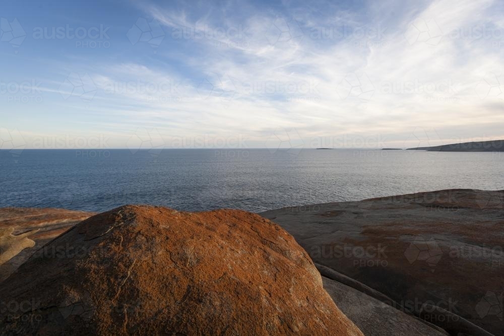 View over flat sea from the orange Remarkable Rocks at sunset - Australian Stock Image