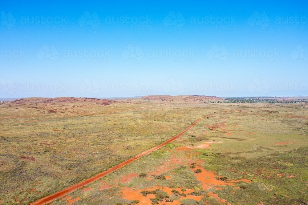 view over low scrub landscape under a blue sky with Karratha in the distance - Australian Stock Image