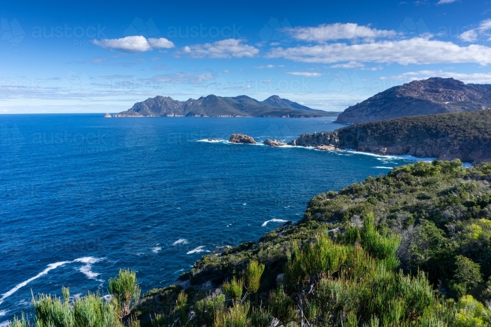 View over ocean and mountains with blue sky and clouds at Freycinet Peninsula - Australian Stock Image