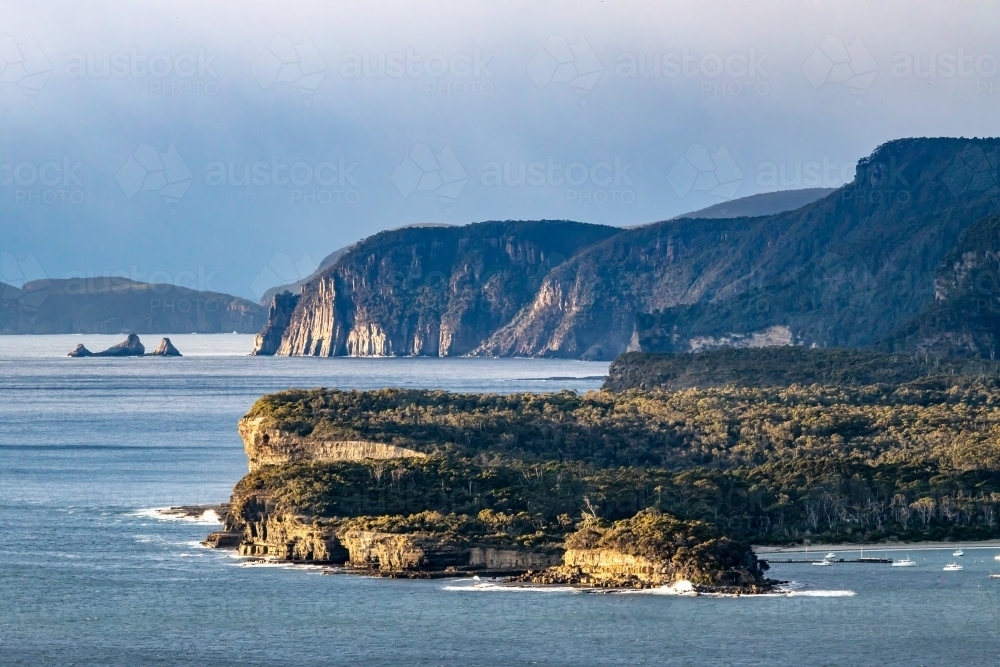 View over Pirates Bay and Tasman Peninsula with sea cliffs, blue water and clear sky - Australian Stock Image