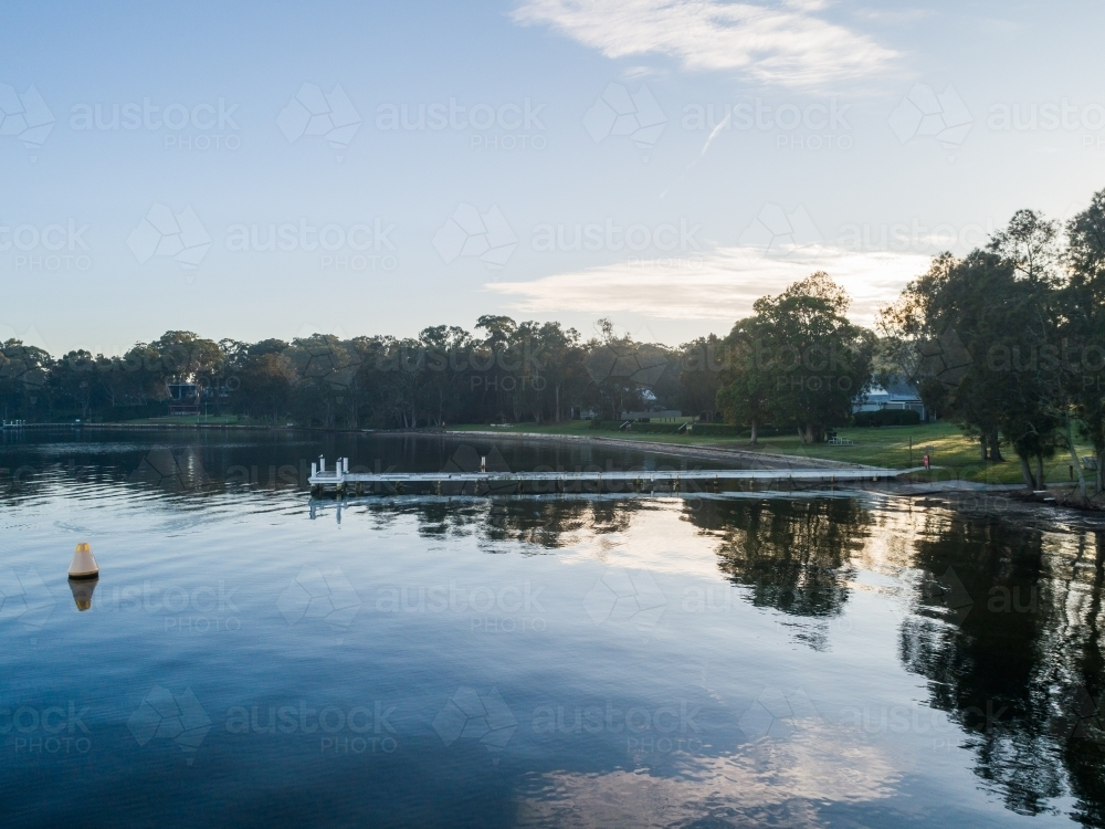 View over water to jetty and lake shoreline - Australian Stock Image