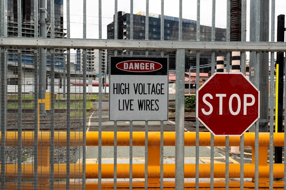 View through barred, signed metal gates with rail lines and buildings - Australian Stock Image