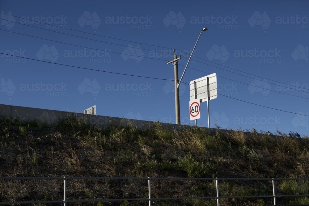 View up grassy verge towards road signs and power lines - Australian Stock Image