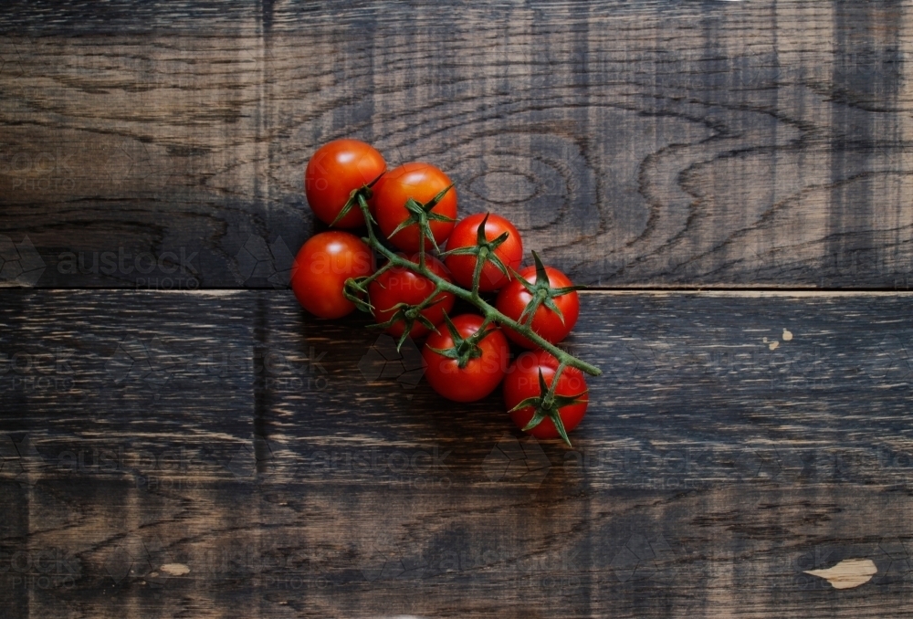 Vine ripened tomatoes on black timber background - Australian Stock Image