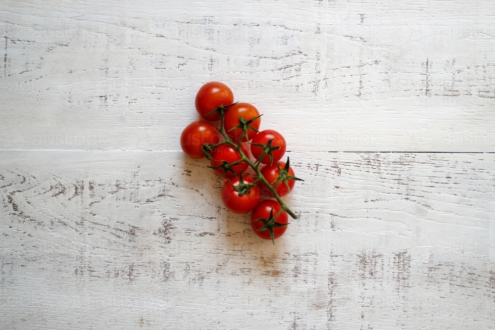 Vine riperned tomatoes on a white wooden background - Australian Stock Image