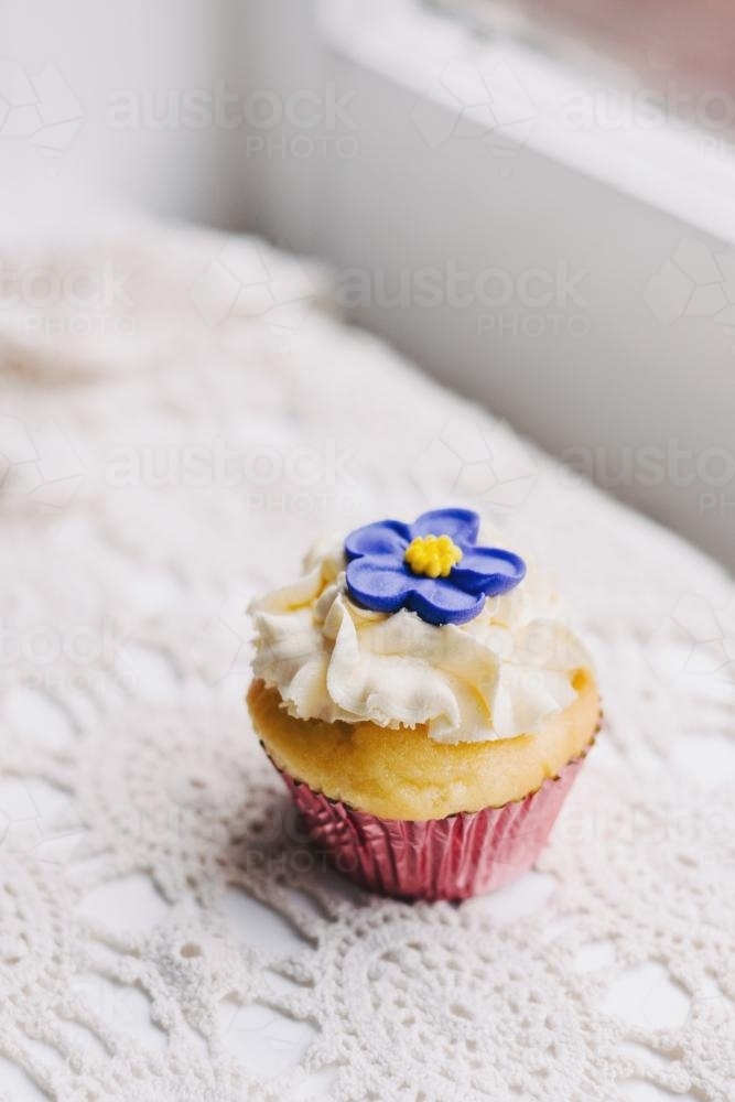 vintage style cupcake on doily with purple flower - Australian Stock Image