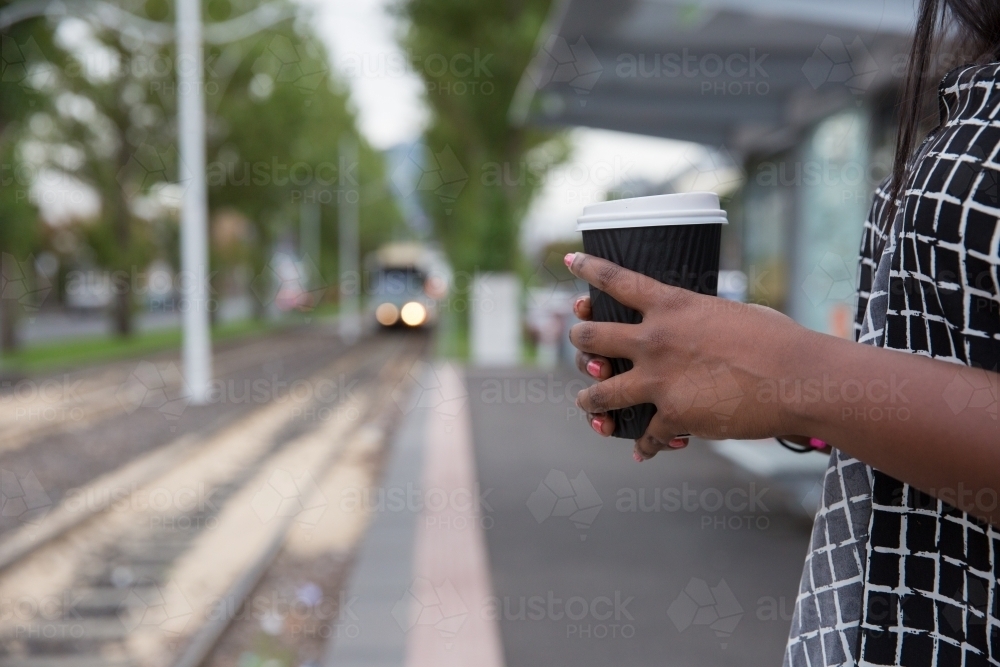 Waiting for the Tram holding takeaway cup - Australian Stock Image