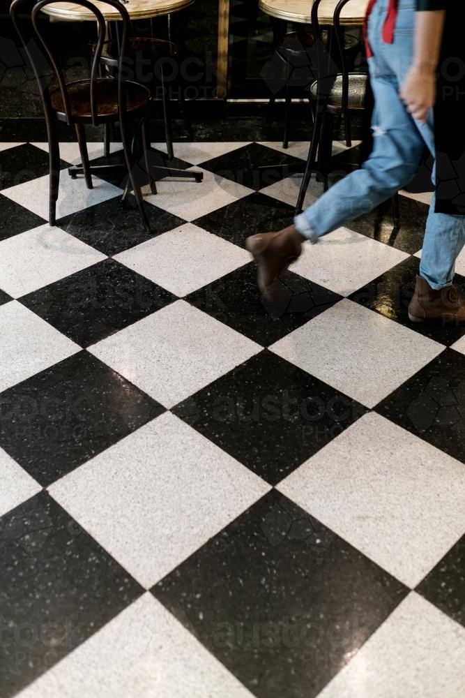Waitress walking on a Chequerboard tiled Floor - Australian Stock Image