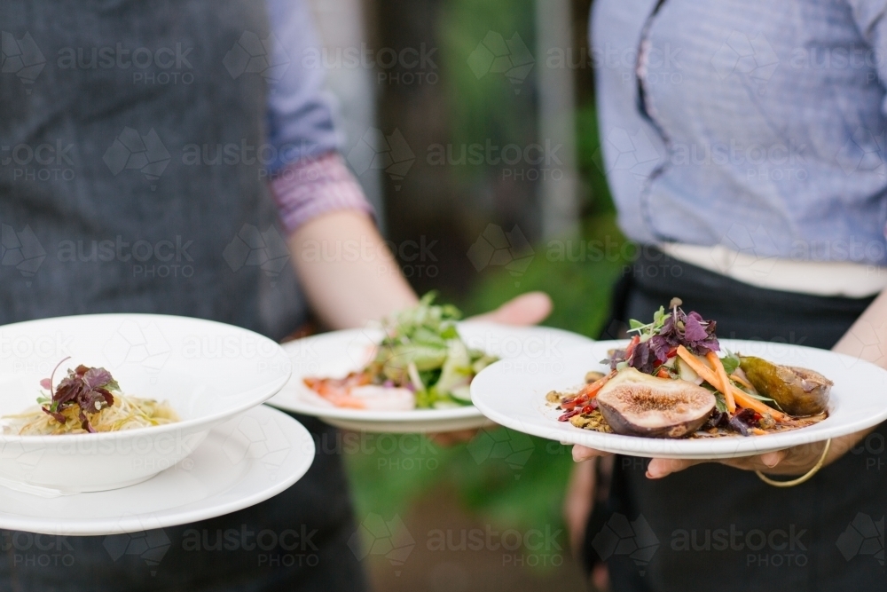 Waitstaff holding plates of food - Australian Stock Image