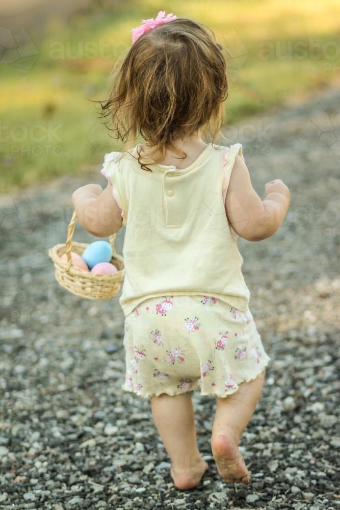 Walking baby carrying a basket of Easter eggs - Australian Stock Image