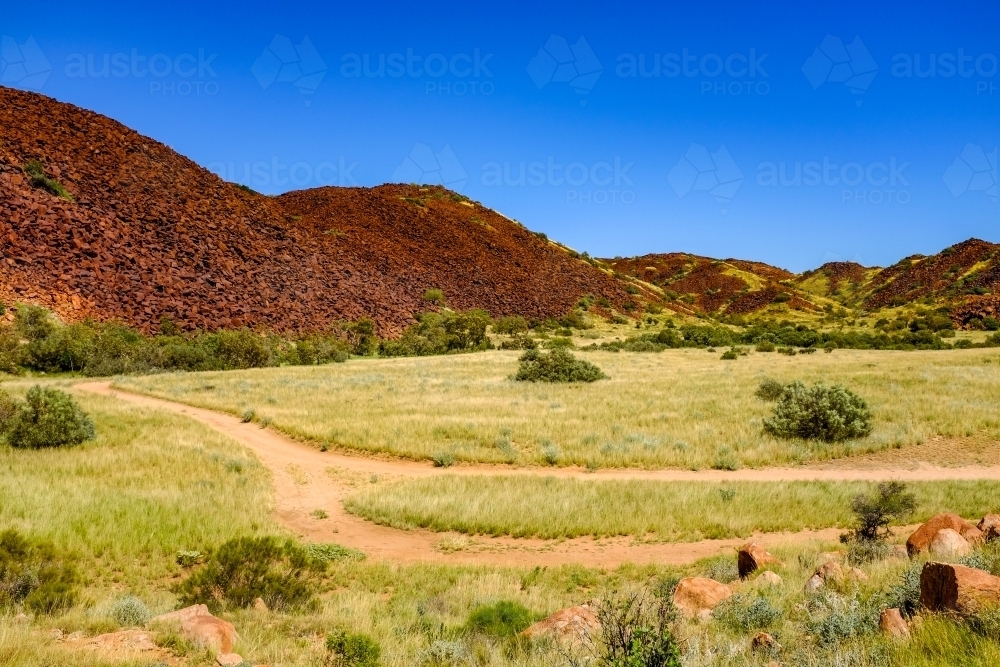 Walking track and red rock mountain off Karratha beach - Australian Stock Image
