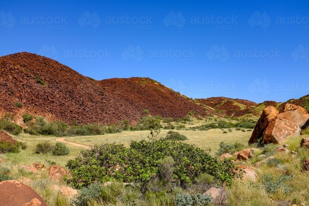 Walking track and red rock mountain off Karratha beach - Australian Stock Image