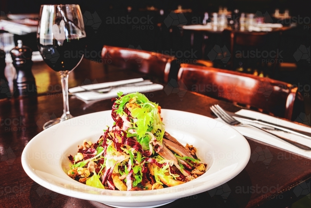 warm lamb salad and red wine in an italian restaurant - Australian Stock Image