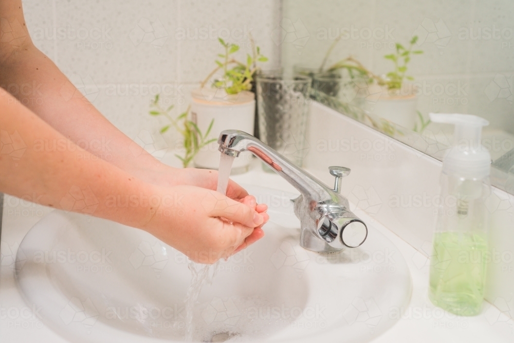 washing hands under water - Australian Stock Image