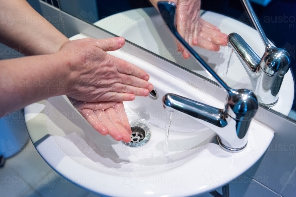 Washing hands with soap and water at basin - Australian Stock Image