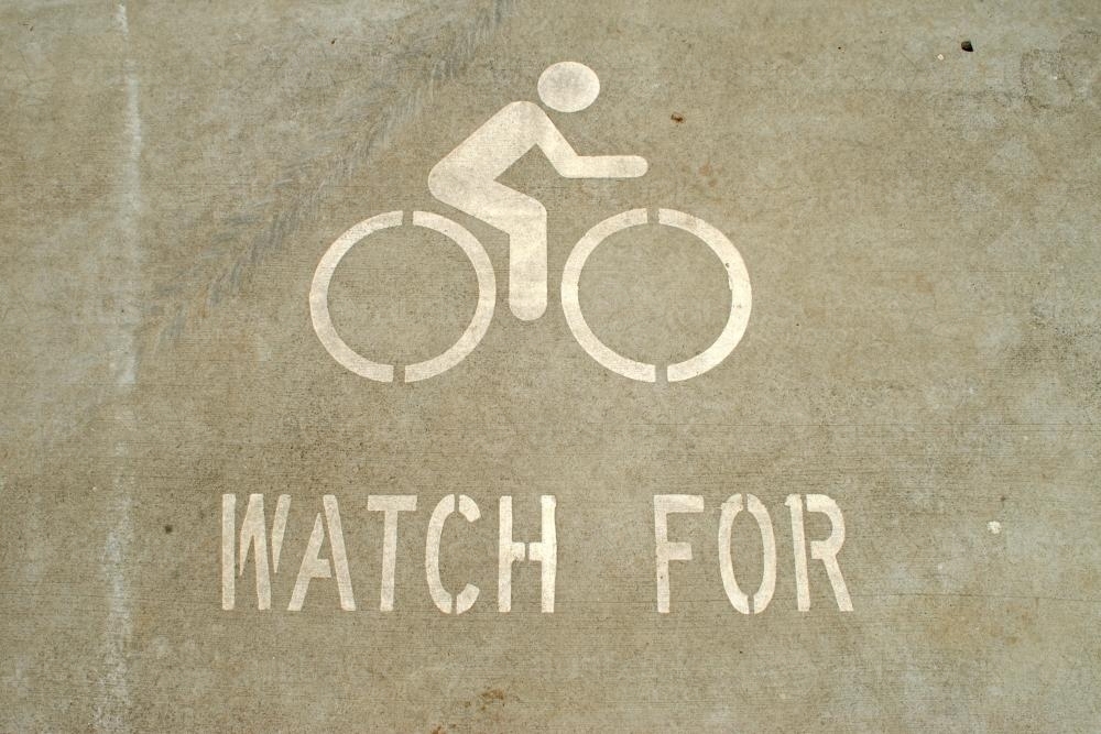 Image of &lsquo;Watch for bicycles&rsquo; sign painted on the road - Austockphoto