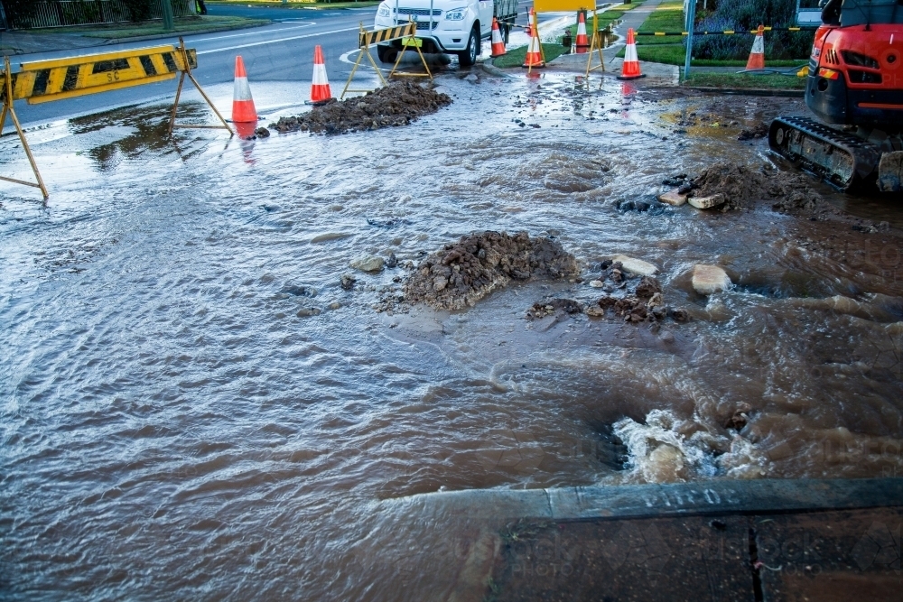 Water and mud over a town road from a broken water main - Australian Stock Image