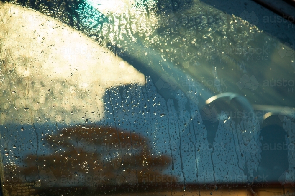 Water droplets running down car window at sunset - Australian Stock Image