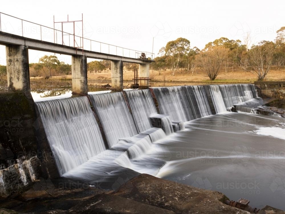Water flowing over a curved concrete dam wall - Australian Stock Image