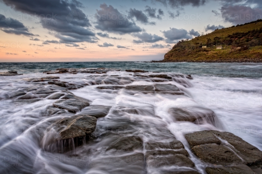 Water flowing over tessellated rocks at Garie Beach Royal N.P. Australia - Australian Stock Image
