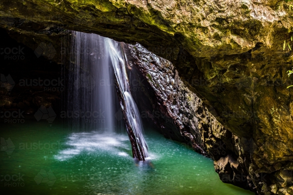 Water flowing through natural arch into underground cave - Australian Stock Image