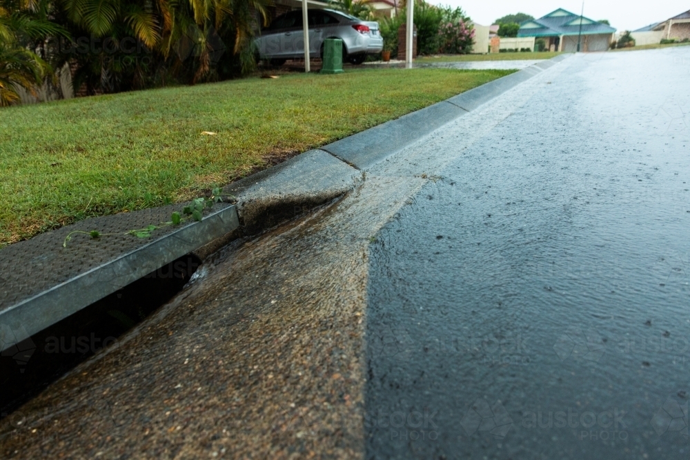 water going down the gutter and drain in a suburban street - Australian Stock Image