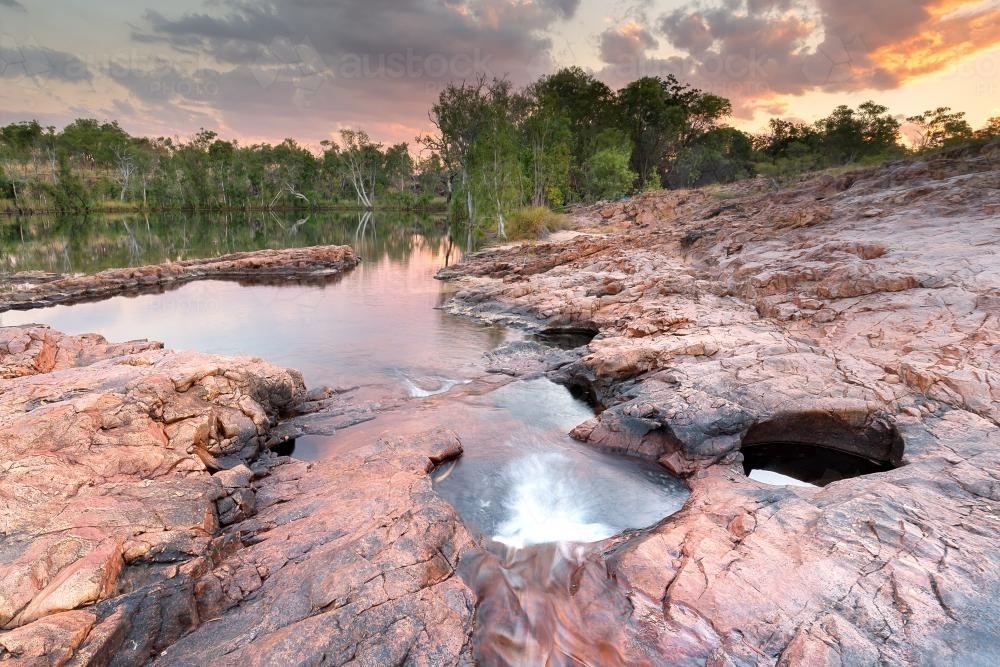 Water hole in rocky outcrop at sunset - Australian Stock Image