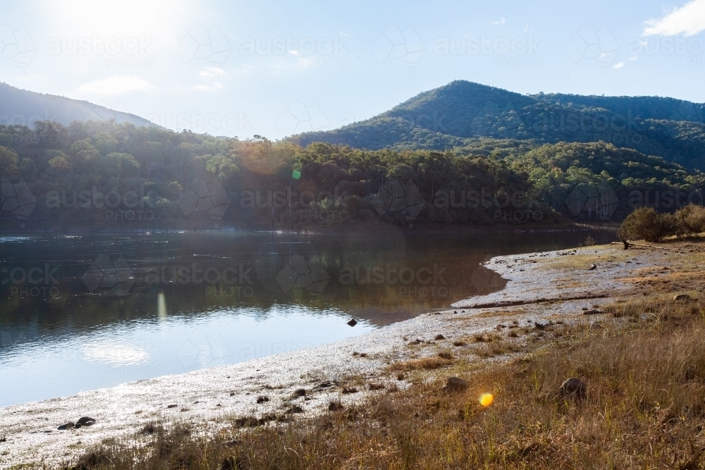 Water in Jounama Pondage at low level with sun flare - Australian Stock Image