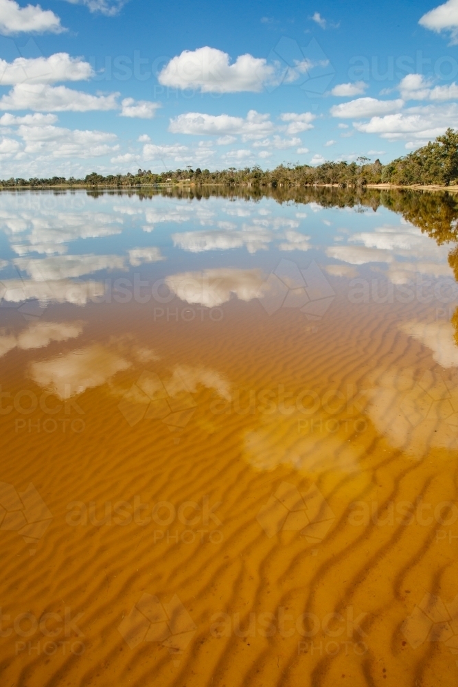 Water reflections of clouds and sky on a glassy lake - Australian Stock Image