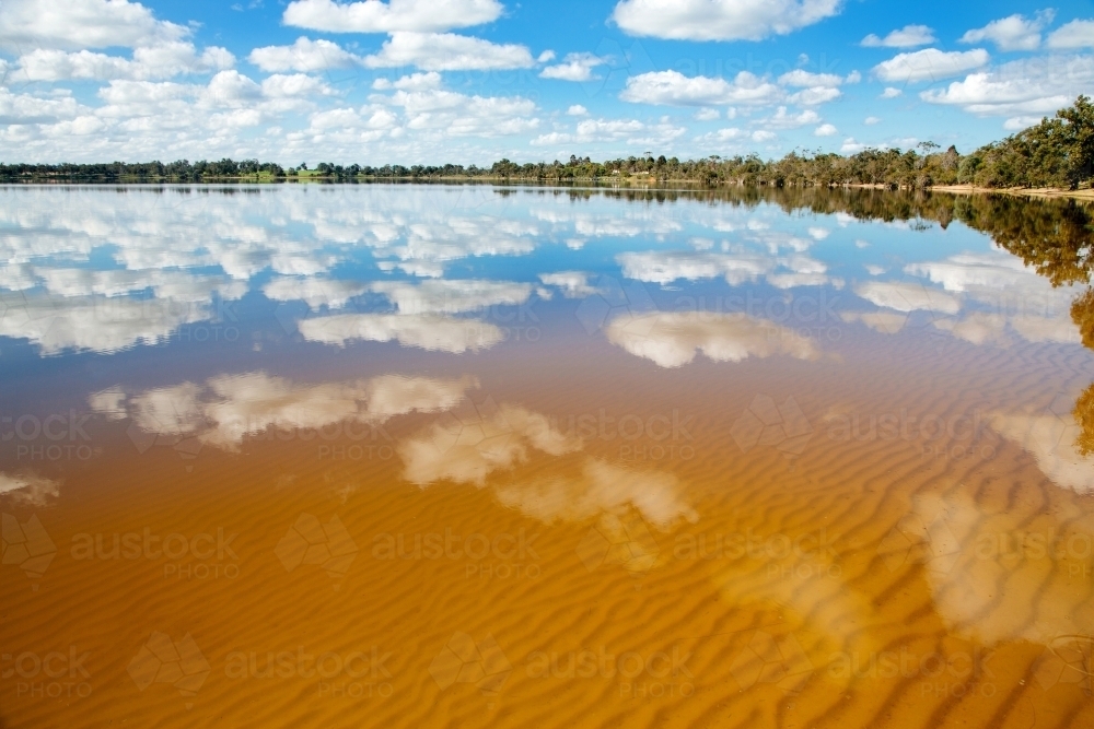 Water reflections of clouds and sky on a glassy lake towerrinning - Australian Stock Image