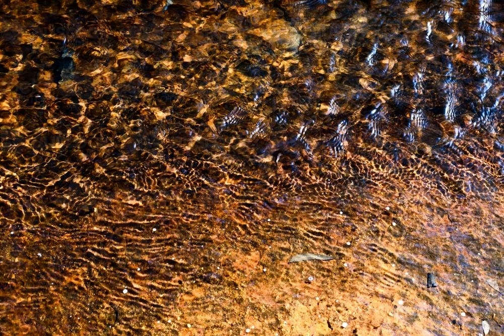 Water rippling over colourful sandstone - Australian Stock Image