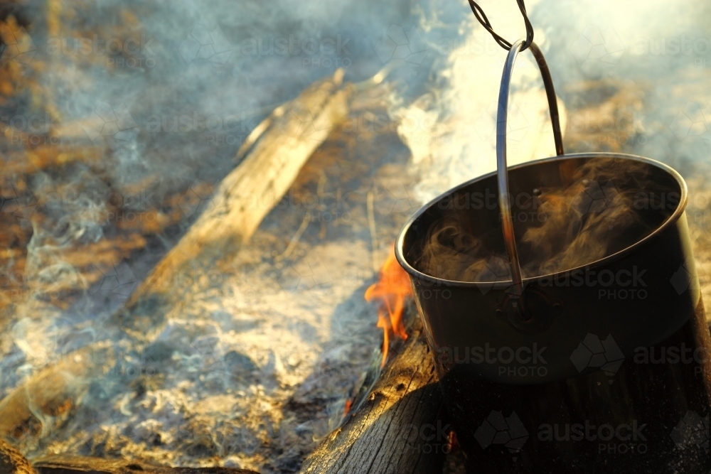Water steaming in the black billy over a campfire - Australian Stock Image