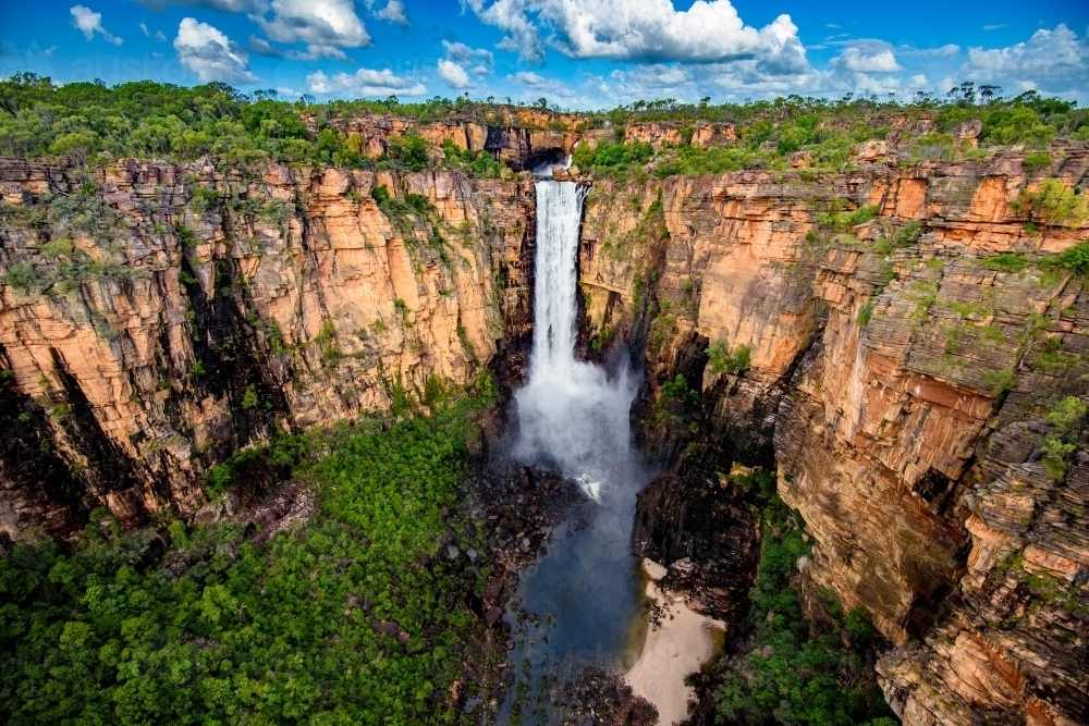Beautiful scene of a full flowing waterfall with golden light and cloudy blue sky - Australian Stock Image