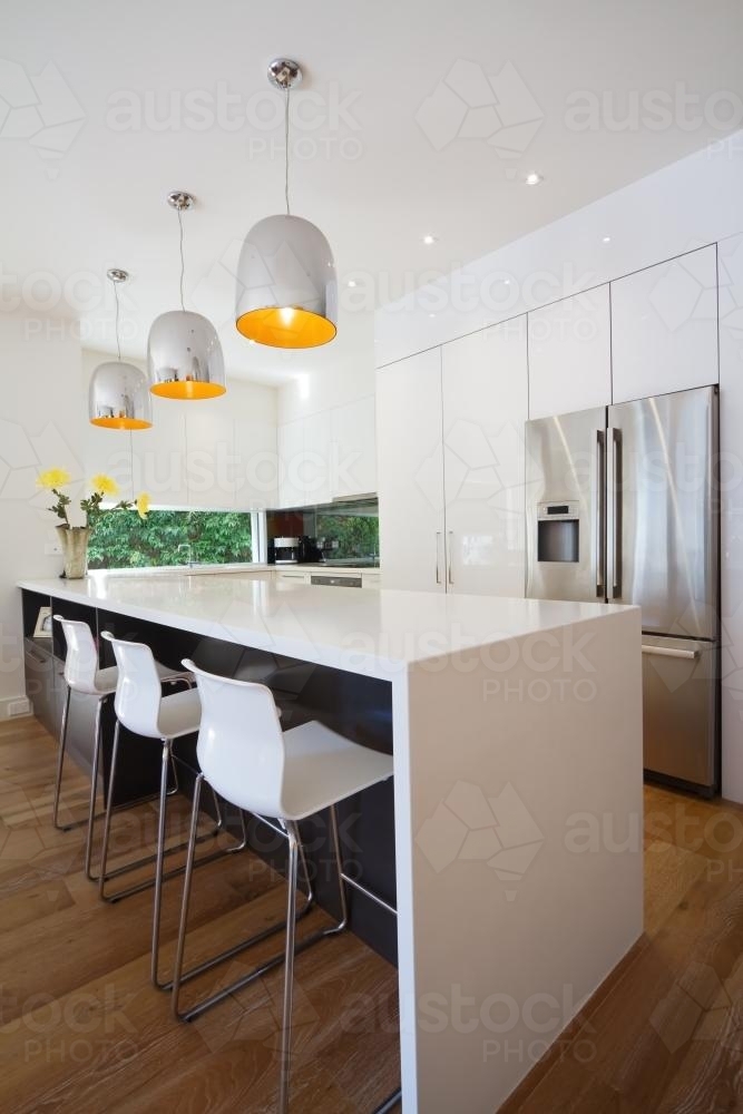 Waterfall style kitchen island bench in contemporary home - Australian Stock Image