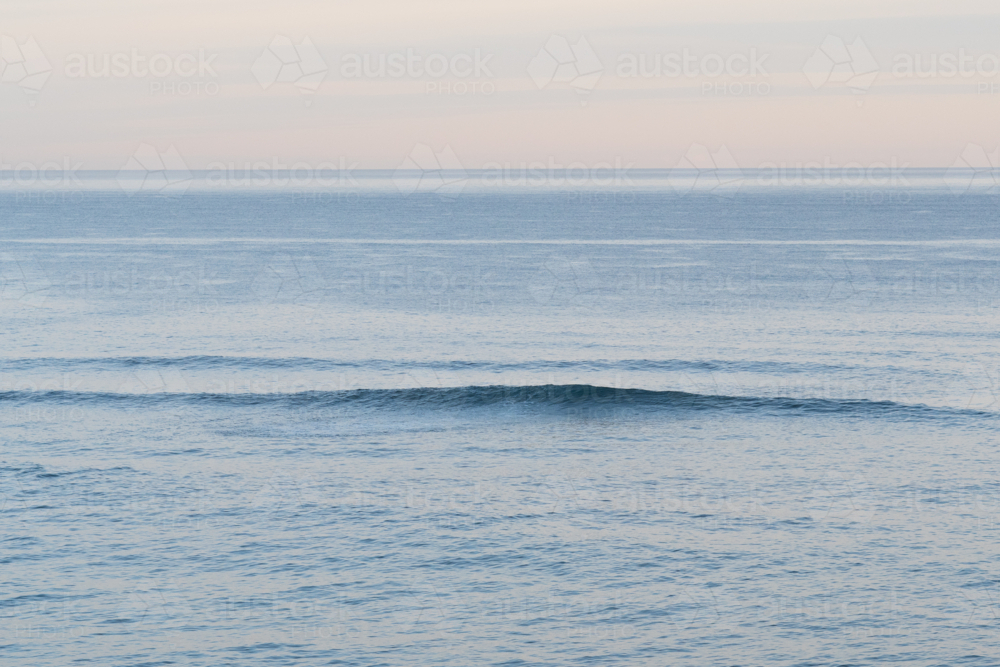 Wave forming on ocean at sunset - Australian Stock Image