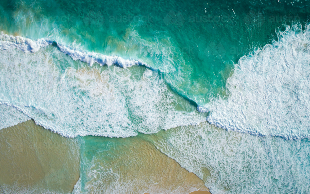 Waves break and recede on a sandy shore - Australian Stock Image