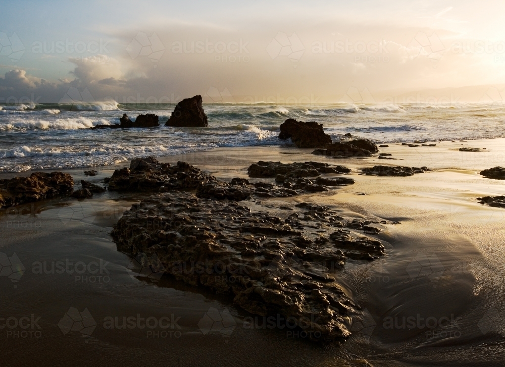 Waves breaking on rocks in evening light - Australian Stock Image