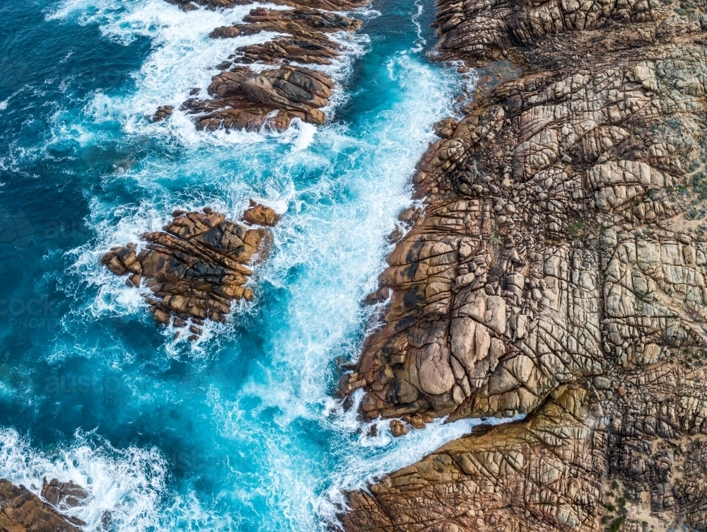Waves crash against rugged coastal rocks - Australian Stock Image
