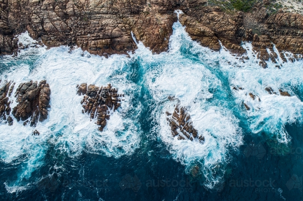 Image of Waves crash against rugged coastal rocks - Austockphoto