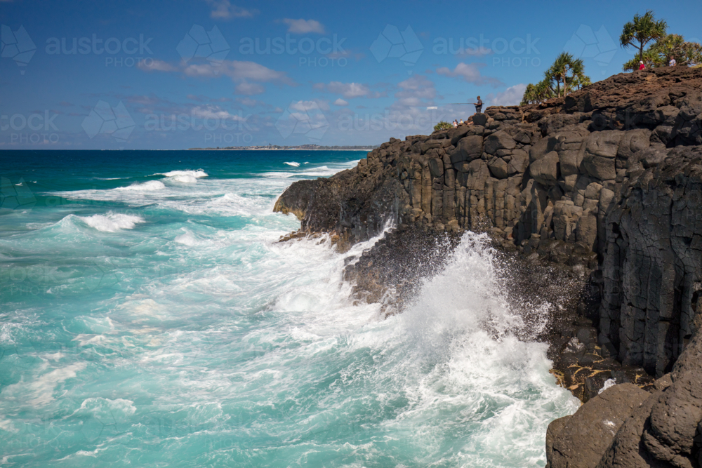 Waves crash upon ancient volcanic rocks at Fingal Head in New South Wales, Australia - Australian Stock Image