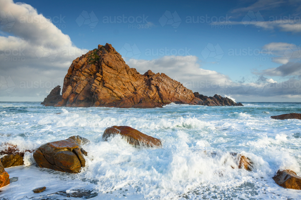 Image of Waves crashing on a rocky shoreline below a prominent coastal ...