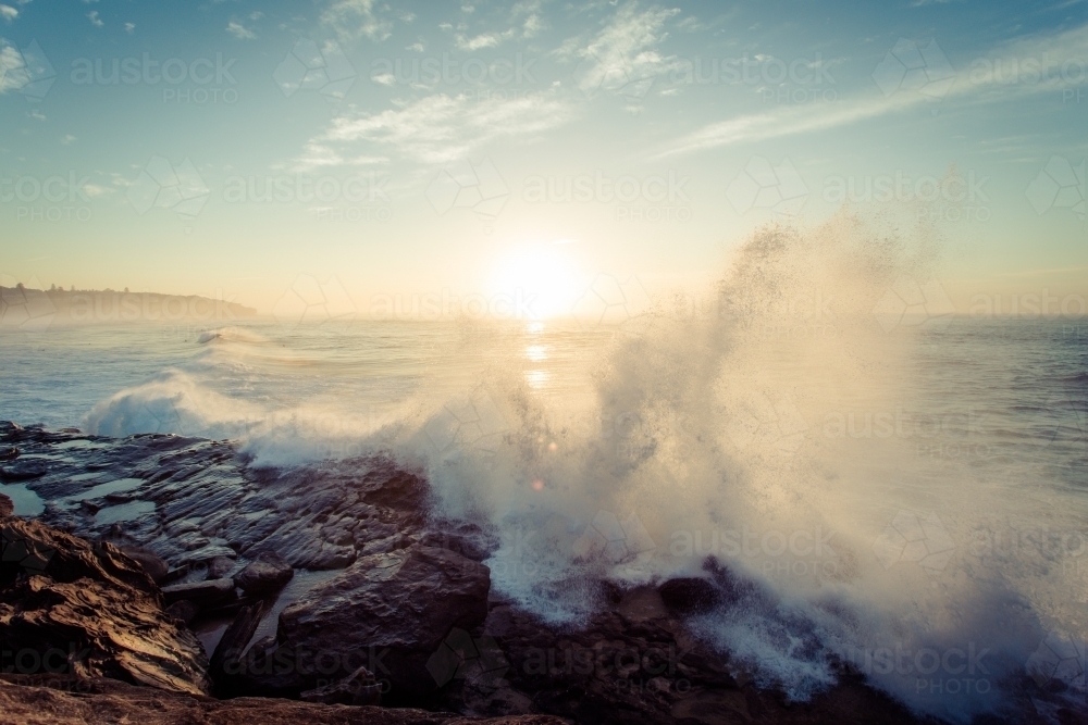 Waves crashing on rocks at sunrise - Australian Stock Image
