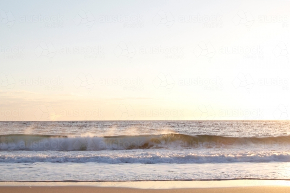 Waves crashing on to the sand at sunrise - Australian Stock Image