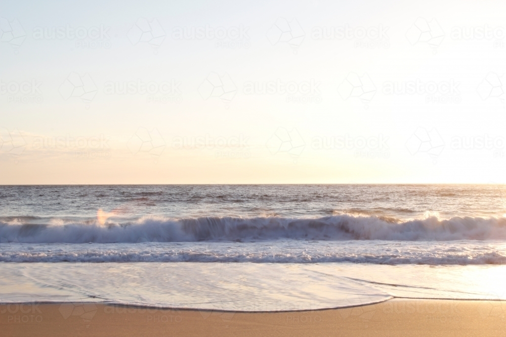 Waves crashing on to the sand at sunrise - Australian Stock Image