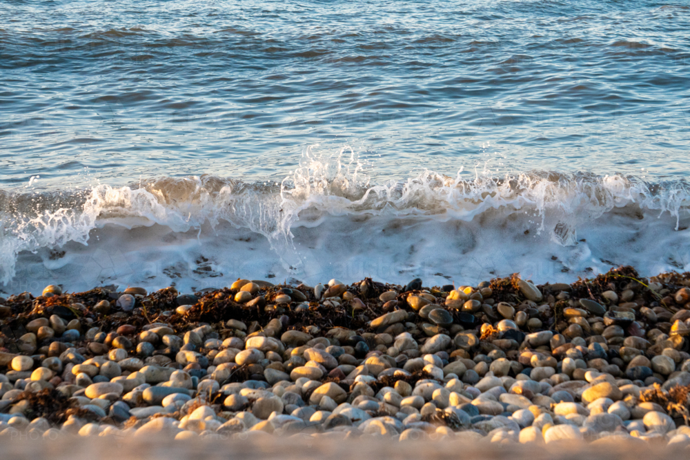 Waves crashing over pebbles - Australian Stock Image