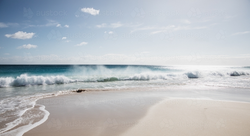 Waves on empty beach in morning light - Australian Stock Image